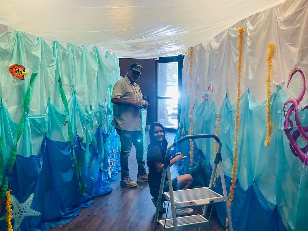 Children decorating an ocean-themed room with blue fabric and colorful sea life details.